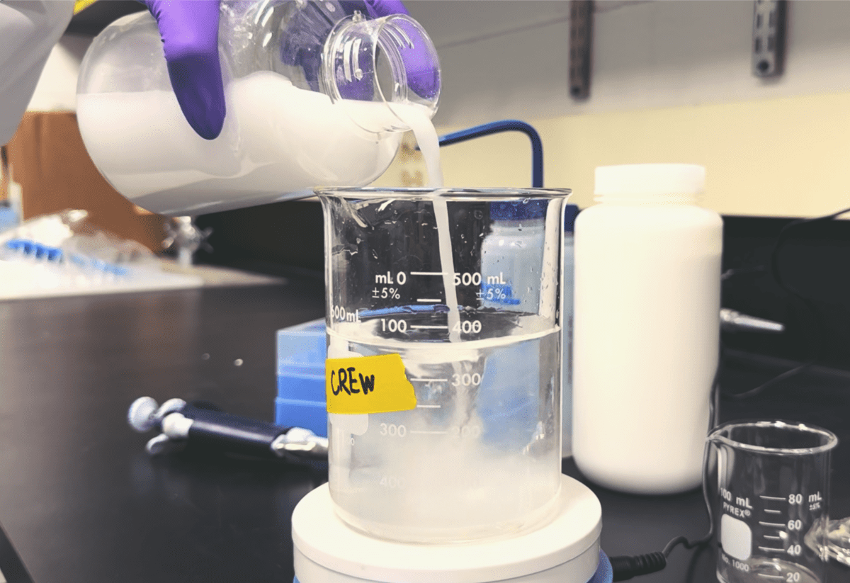 A scientist pouring a liquid solution into a beaker